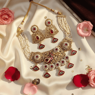 Ornate gold and red jewelry set with flowers on a beige fabric background