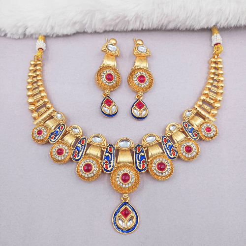Gold necklace and earrings set with red and blue accents on a light gray background