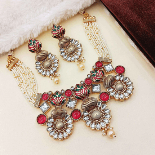 Ornate gold, red, and green jewelry set on a white background