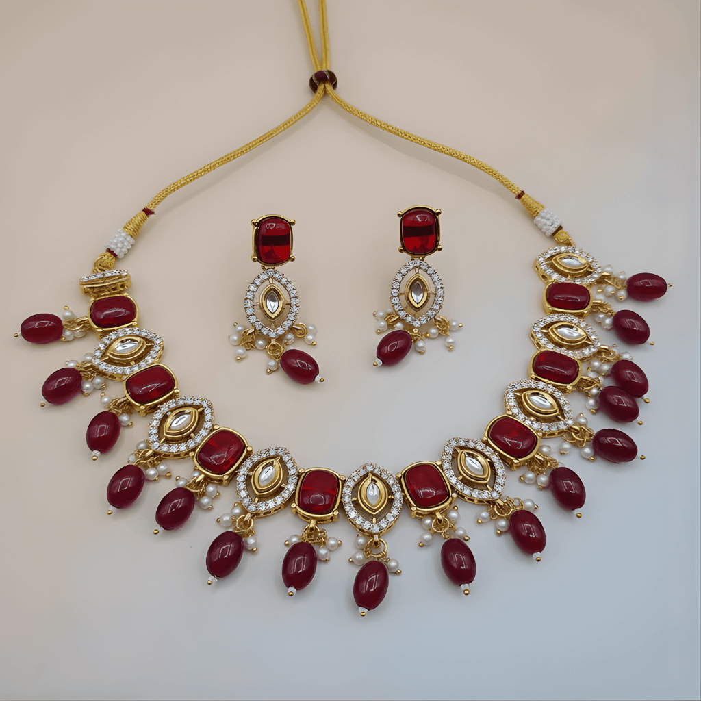 Jewelry set with necklace and earrings featuring red stones and gold accents on a light background