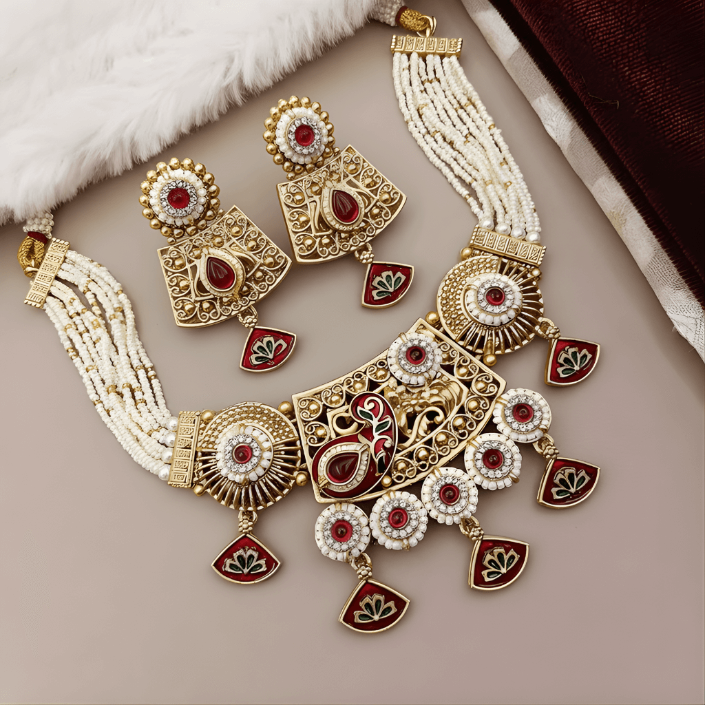 Ornate necklace and earrings set with red stones on a soft surface