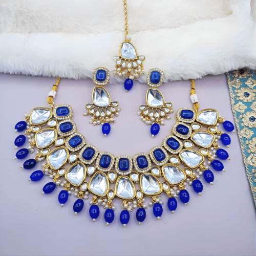 Ornate jewelry set with blue and gold elements on a white surface