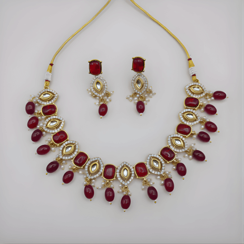Jewelry set with necklace and earrings featuring red stones and gold accents on a white background