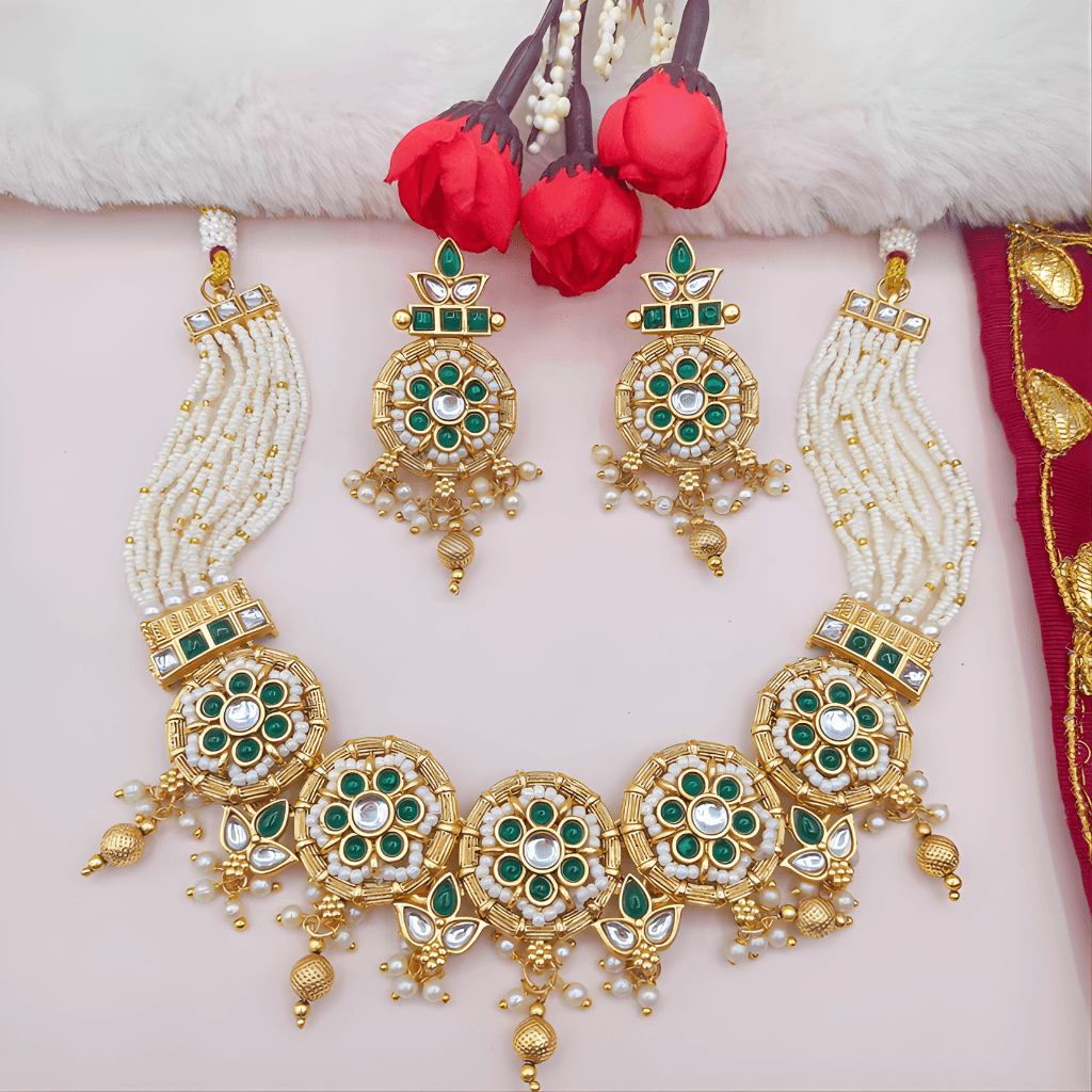 Ornate gold necklace with green and white stones on a light pink background
