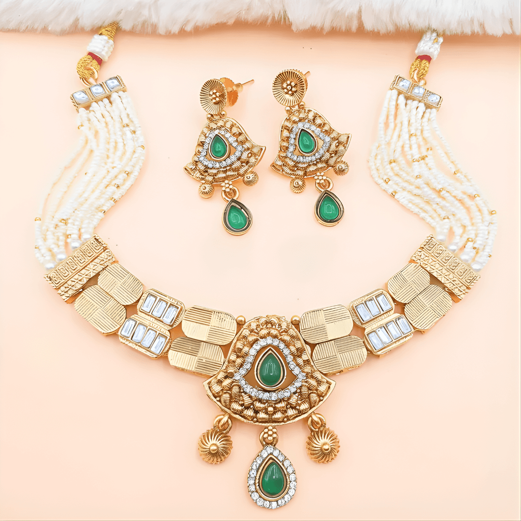 Gold necklace with green gemstones and matching earrings on a beige background