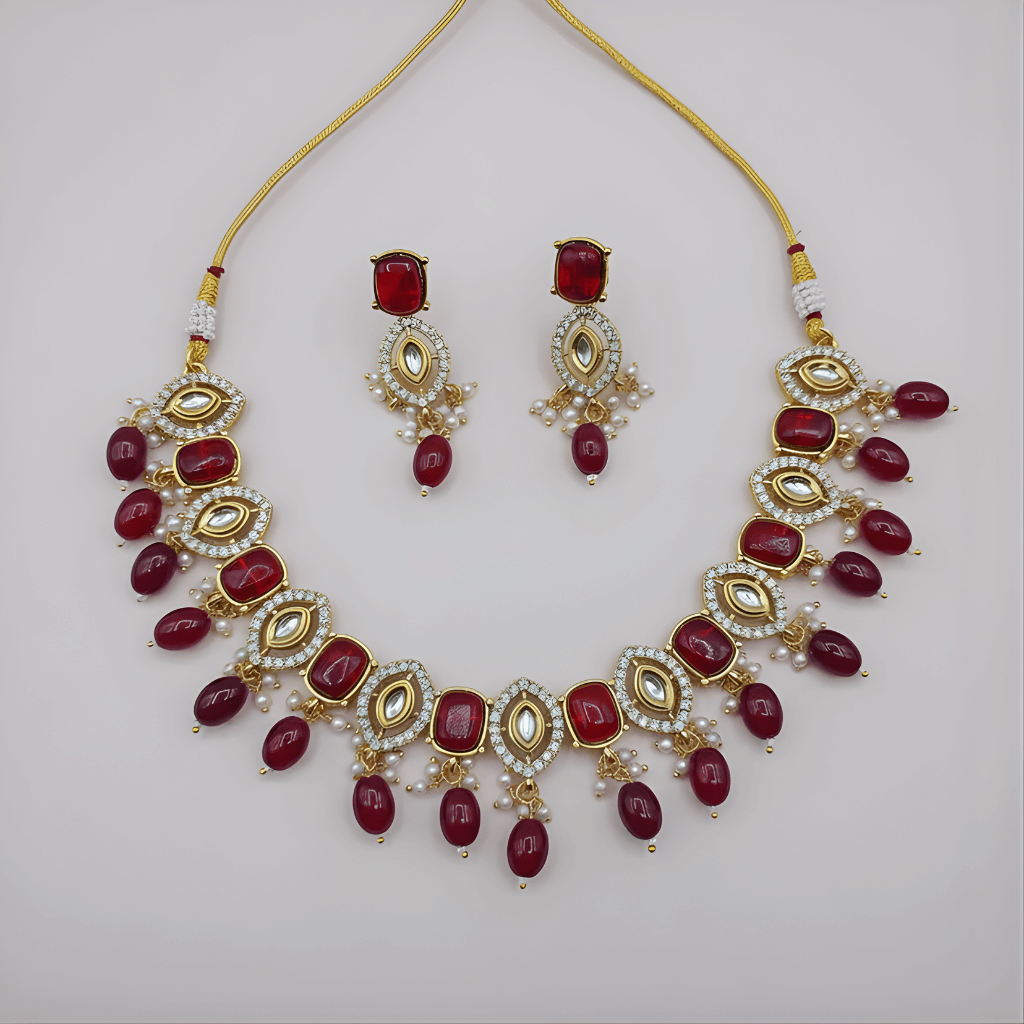 Jewelry set with necklace and earrings featuring red stones on a light gray background