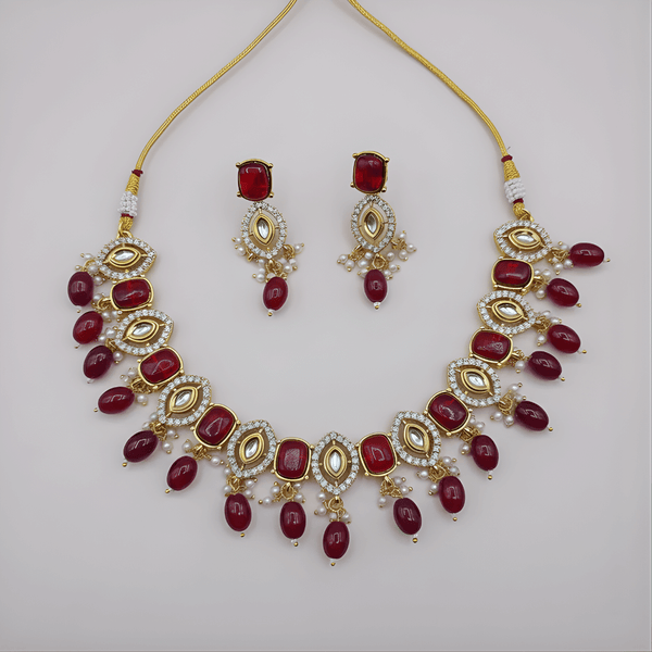 Jewelry set with necklace and earrings featuring red stones on a light gray background