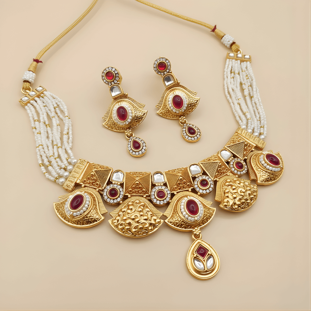 Gold necklace and earrings with red and white stones on a beige background