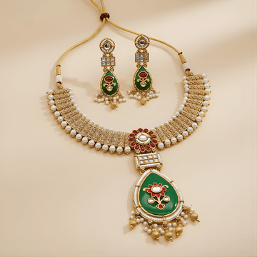 Ornate necklace and earrings set with green and red accents on a beige background