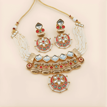 Ornate gold necklace with red, green, and white stones on a beige background