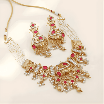 Ornate gold necklace with red stones and pearl accents on a beige background