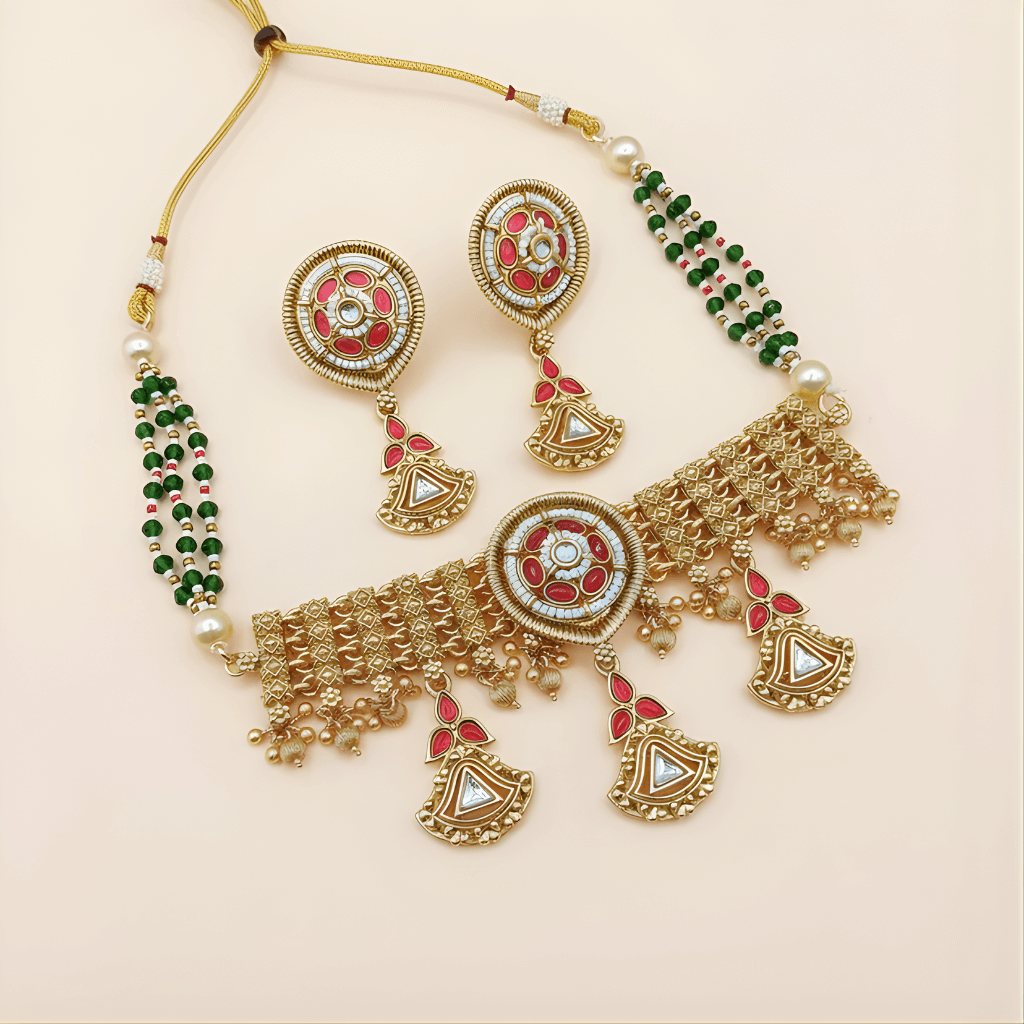 Ornate gold necklace with red and green accents on a beige background