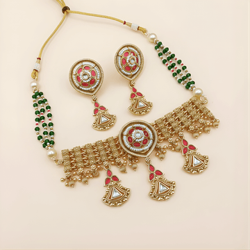 Ornate gold necklace with red and green accents on a beige background