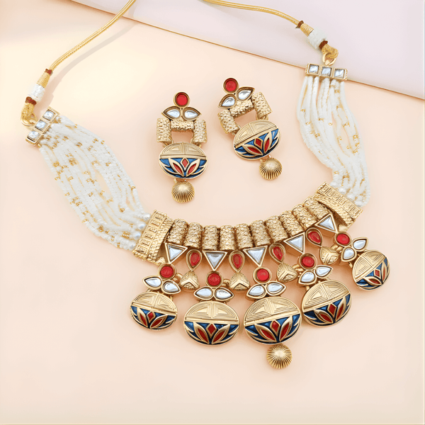 Ornate gold necklace with red and blue accents on a light pink background