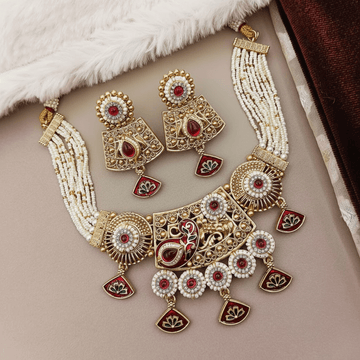 Ornate gold, red, and white jewelry set on a soft surface
