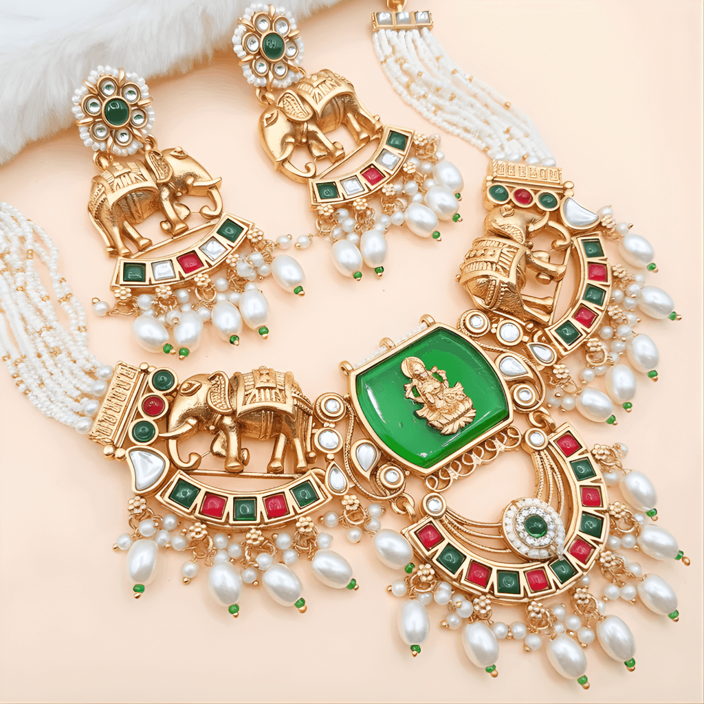 Ornate gold necklace with green gemstone and pearl accents on a beige background