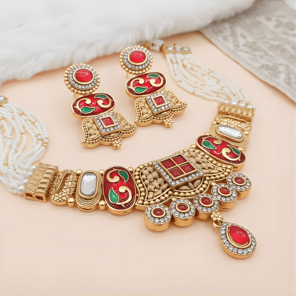 Ornate gold necklace with red and green accents on a soft beige background