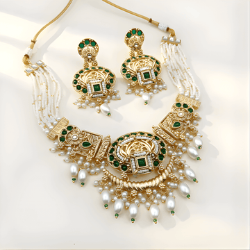 Gold necklace with green gemstones and pearl drops on a white background