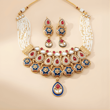 Ornate necklace and earrings set with gold, blue, and red stones on a beige background