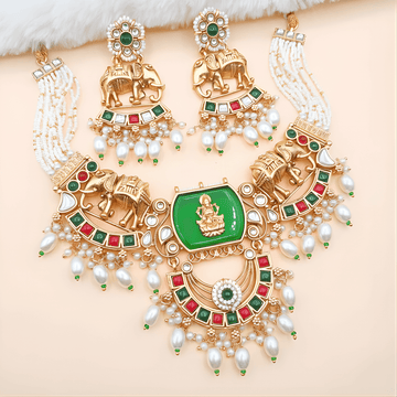 Ornate gold necklace with green gemstone and pearl accents on a beige background