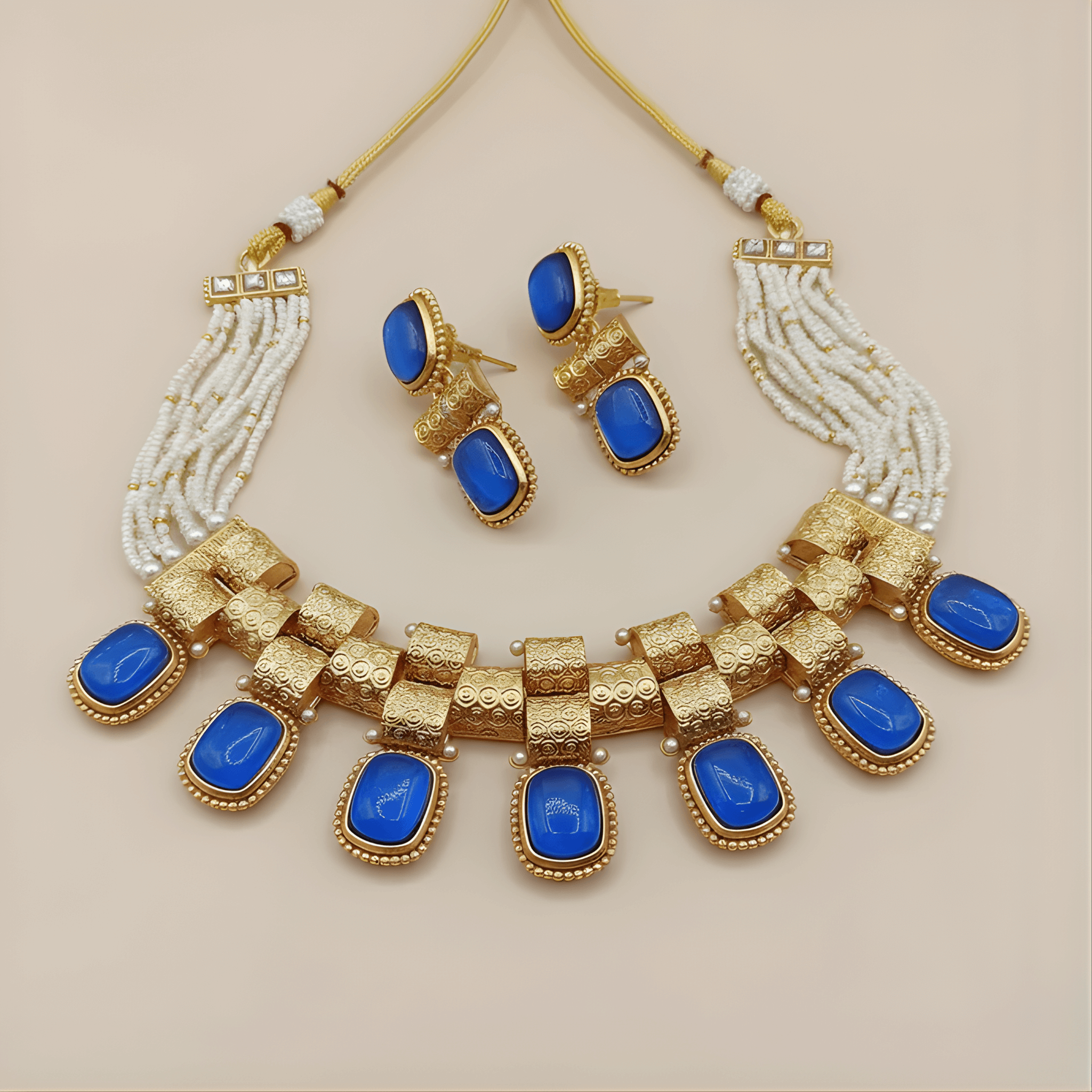 Jewelry set with gold necklace and earrings featuring blue stones on a beige background