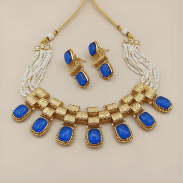 Jewelry set with gold necklace and earrings featuring blue stones on a beige background